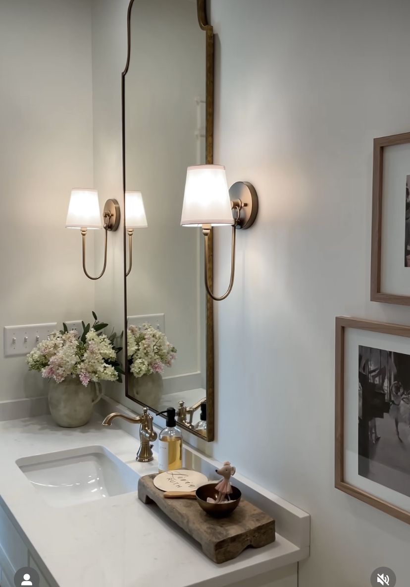 Guest bathroom with large vintage mirror and classic gold sconces