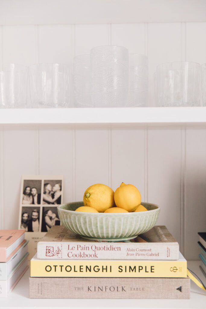 fruit bowl filled with bright yellow lemons resting on cooking books