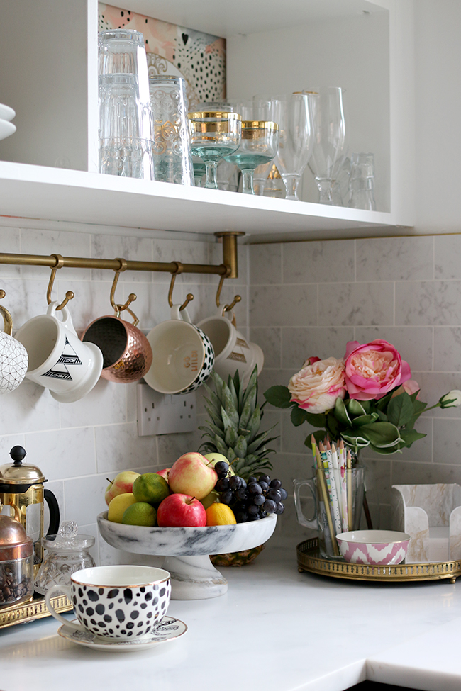 kitchen counter decorated with various objects and hanging cups from a bronze rod