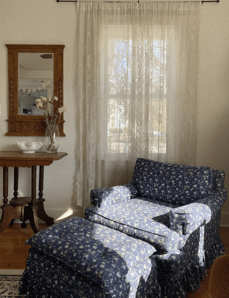 Vintage blue floral armchair with matching footrest used in a reading corner