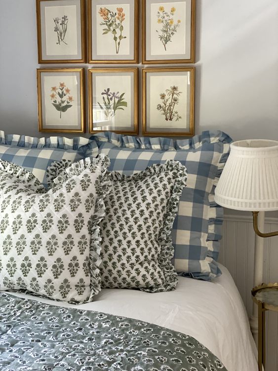 Gallery wall of botanical prints hanging over a bed with light blue gingham bedding