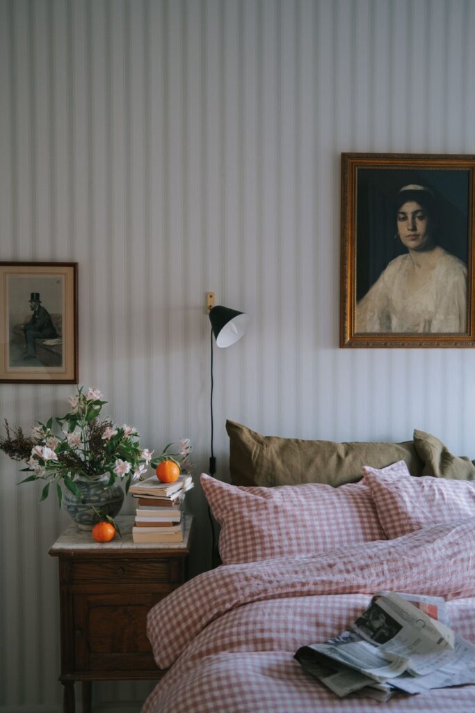 Antique portrait painting of a woman hanging on the wall above the bed in a cottage core bedroom