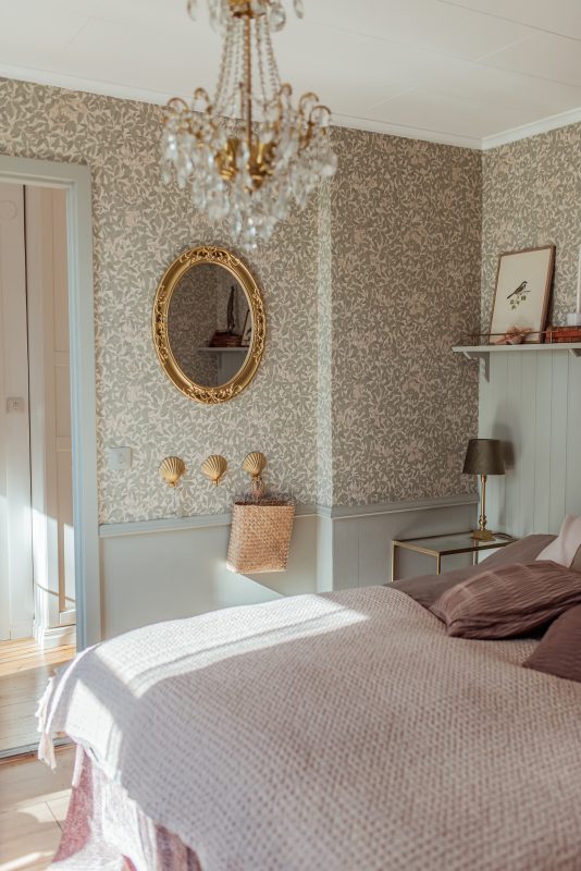 Classy elegant bedroom with gold vintage mirror hanging on the wall