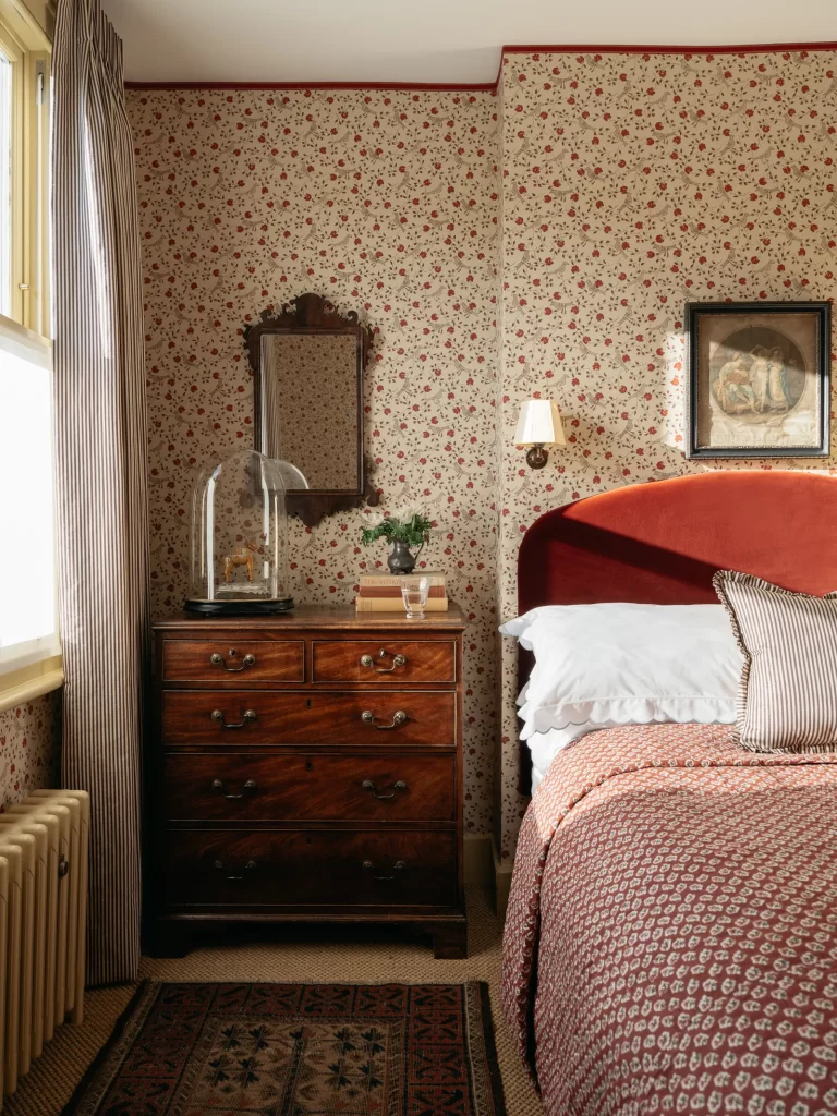 Cottagecore bedroom in red tones with vintage rug layered on top of carpet