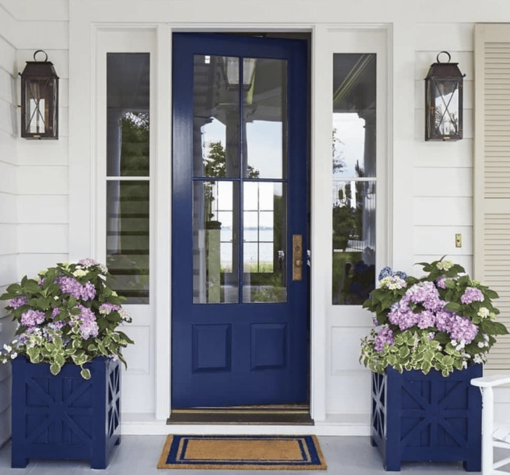 Blue front door with matching planters and colorful flowers 