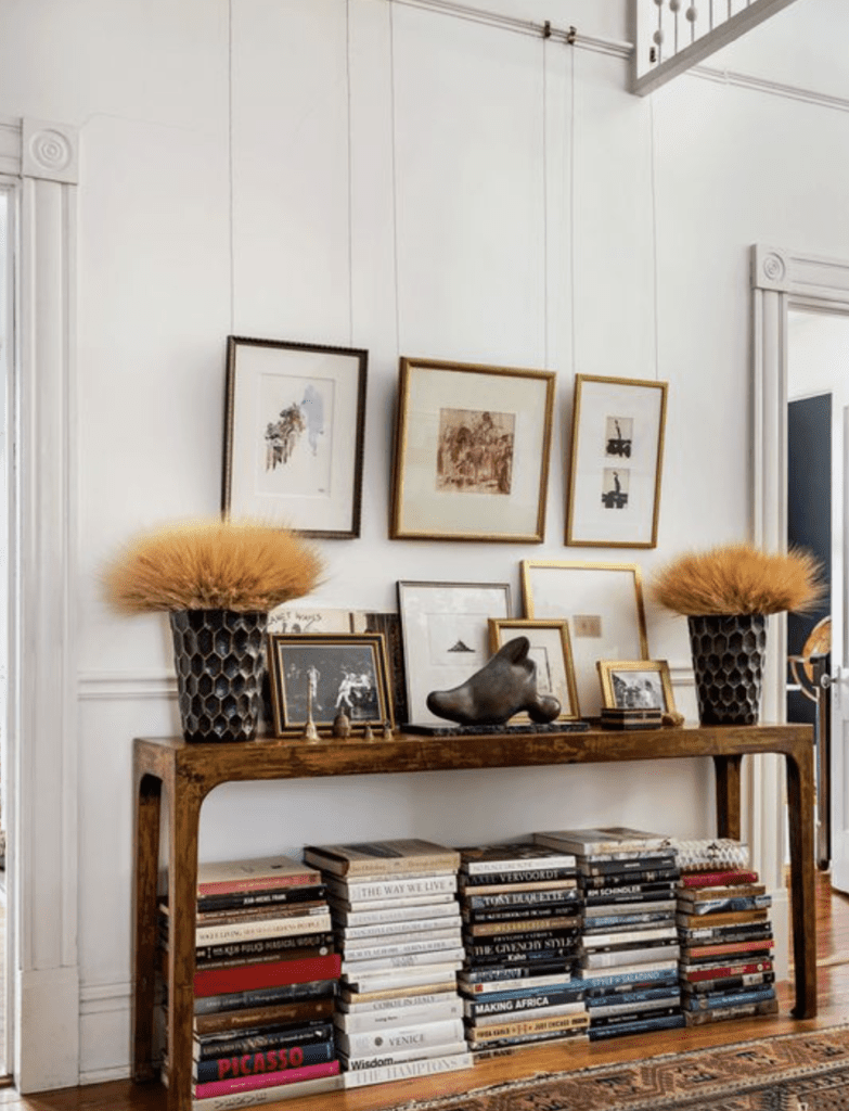 Entryway where books are stacked in tall piles to complement the furniture