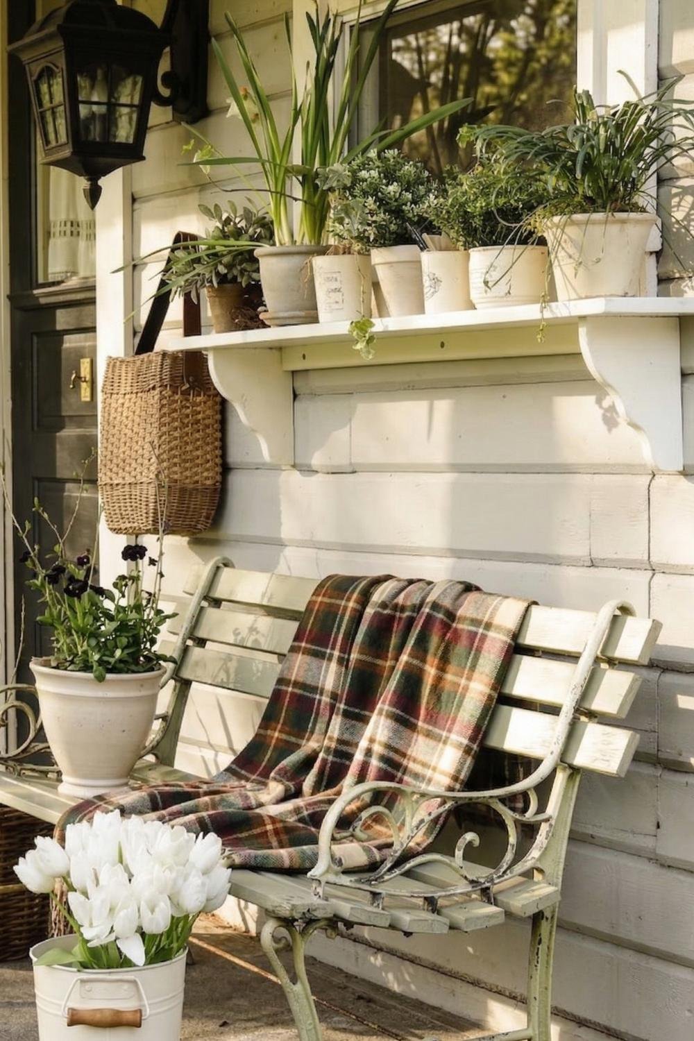 Vintage garden bench on a sunny cottage porch with a dark plaid throw blanket and a bucket of white tulips.