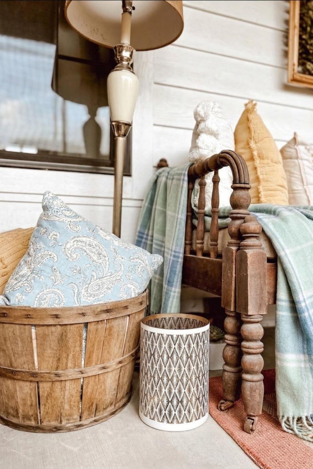 Vintage wooden daybed styled with a light blue paisley pillow and a green plaid cashmere blanket in a cozy cottage nook.